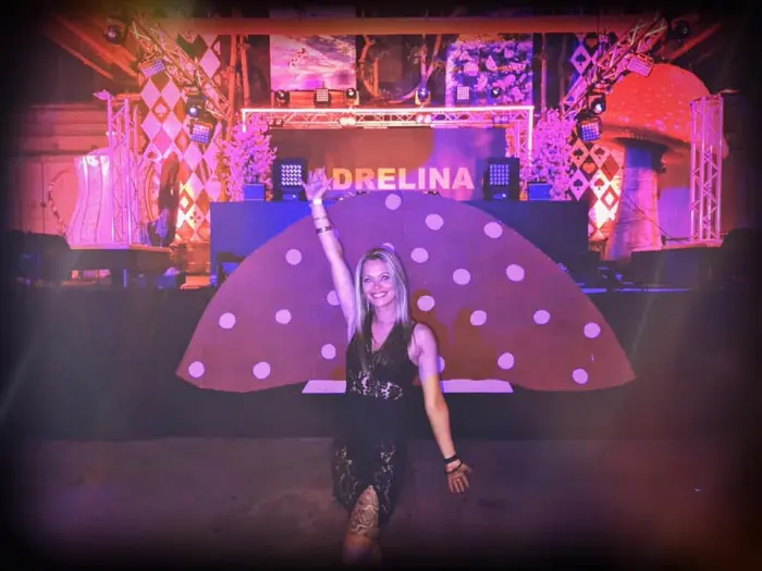 Adrelina on a pink stage with her name on the screen behind her