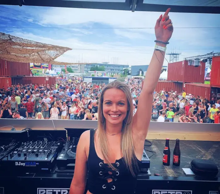Adrelina with one arm raised in front of a packed festival crowd