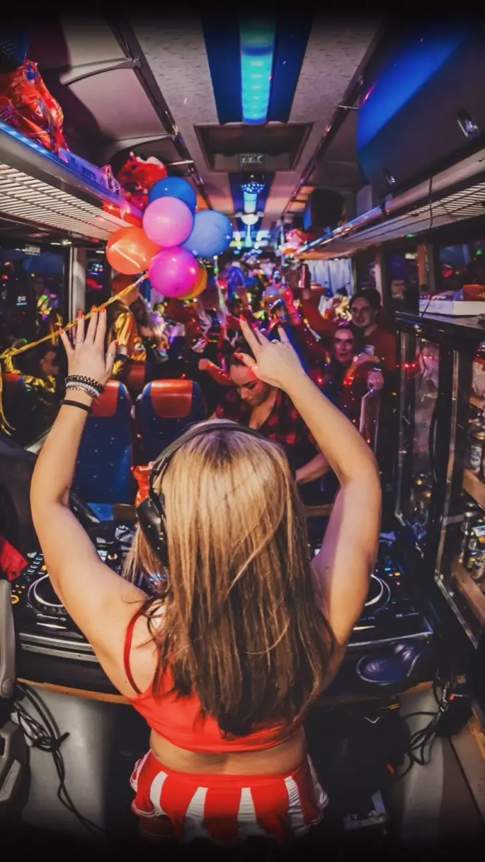 Adrelina with both arms up on a party bus full of balloons